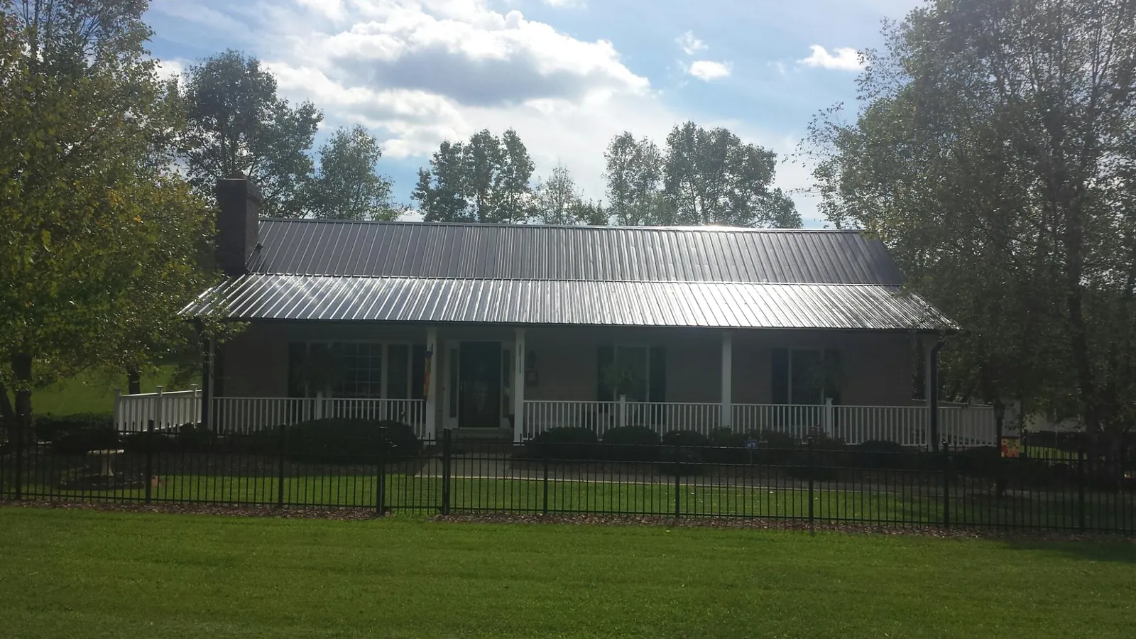 Gray metal roof on a brick ranch with a full width front porch — Gutter Guard Installation work by our crew in Fulton